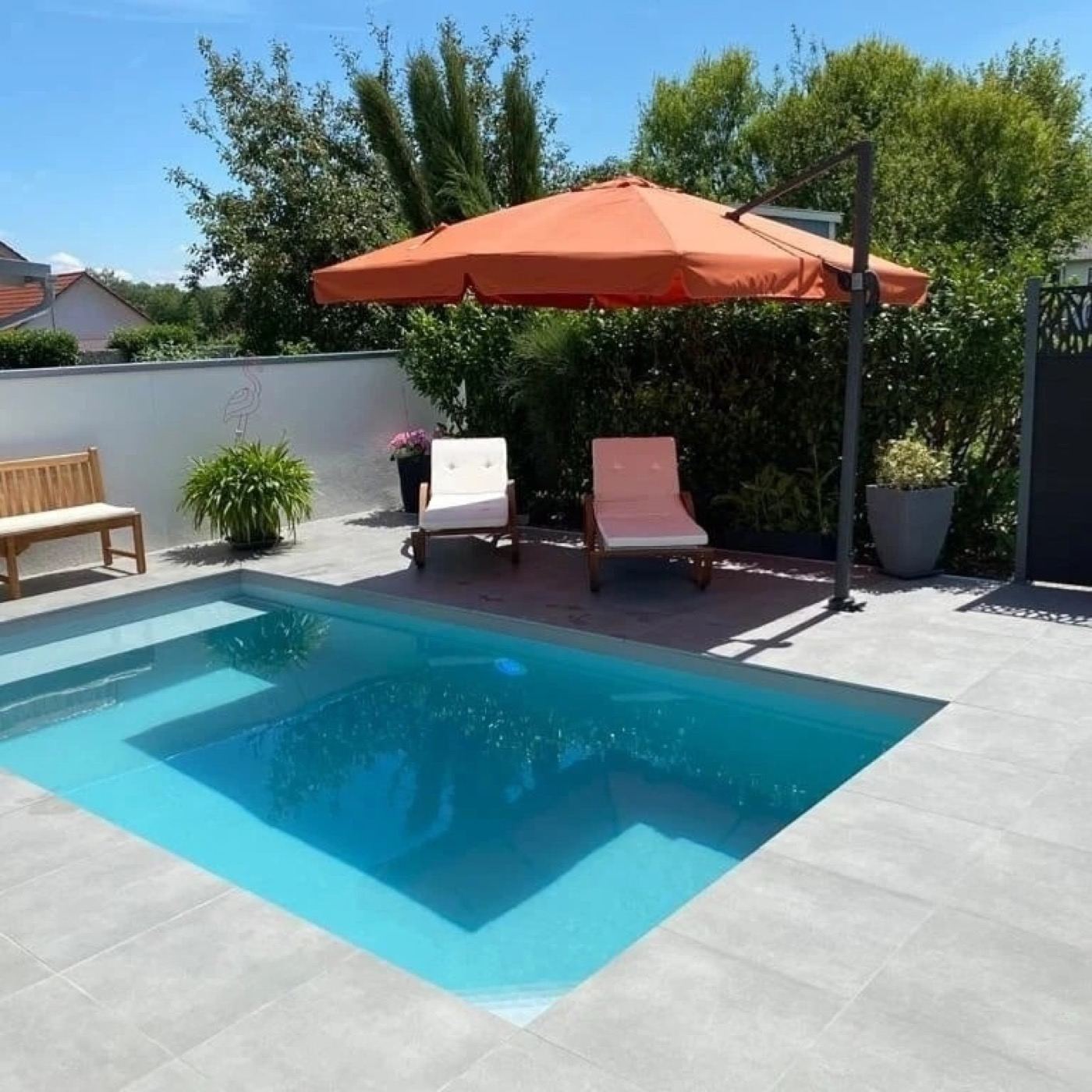 Pool mit hellen Bodenplatten und orangem Sonnenschirm